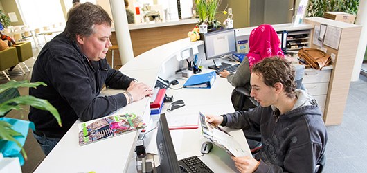 man staat bij de balie in gesprek met een baliemedewerker